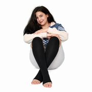 Woman seated wearing black knee-high open-toe wide-calf compression socks.